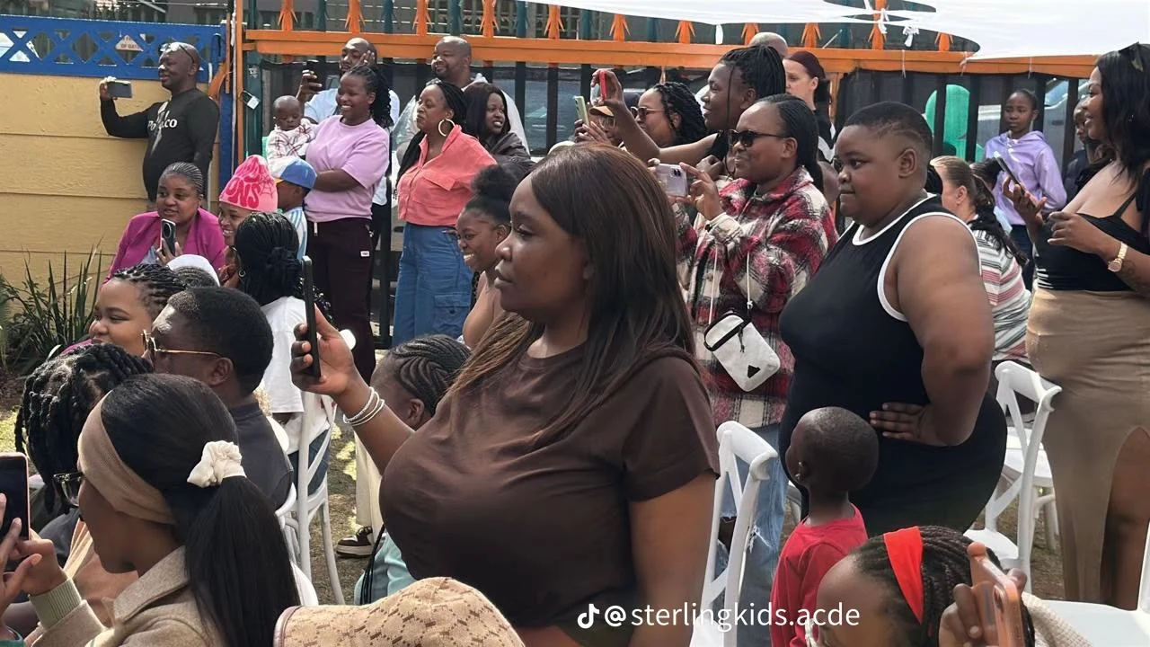Families and community members watch and record an academy performance.