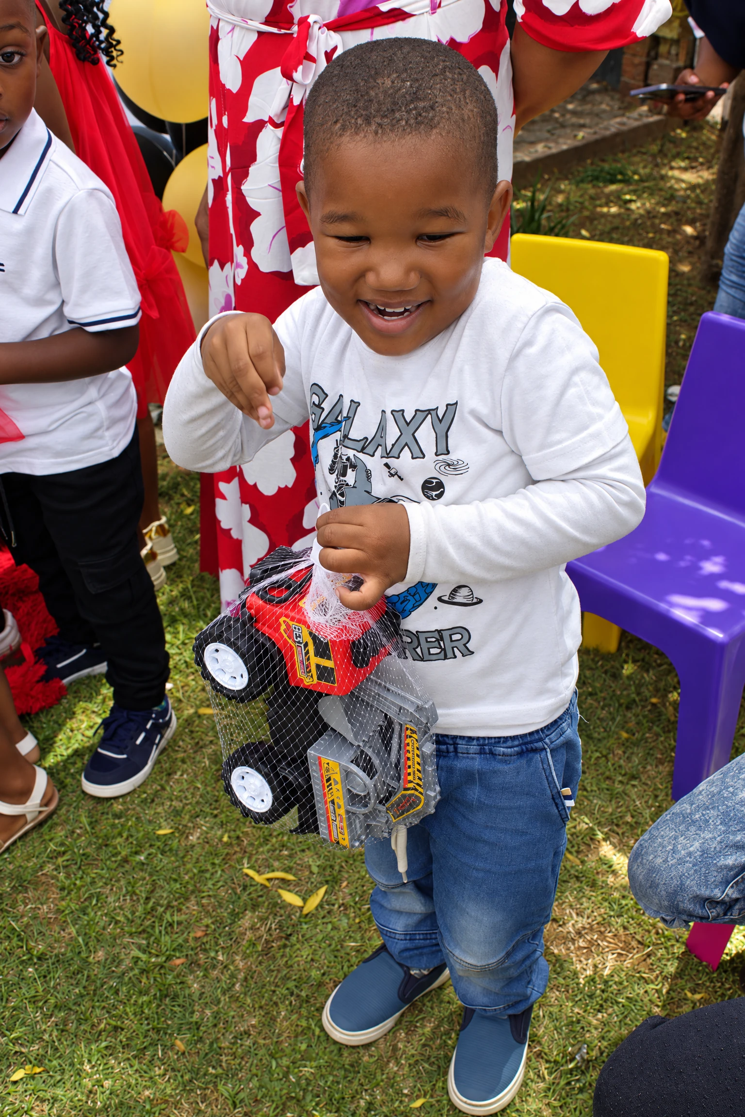 A smiling little learner holds a toy truck at an academy celebration.