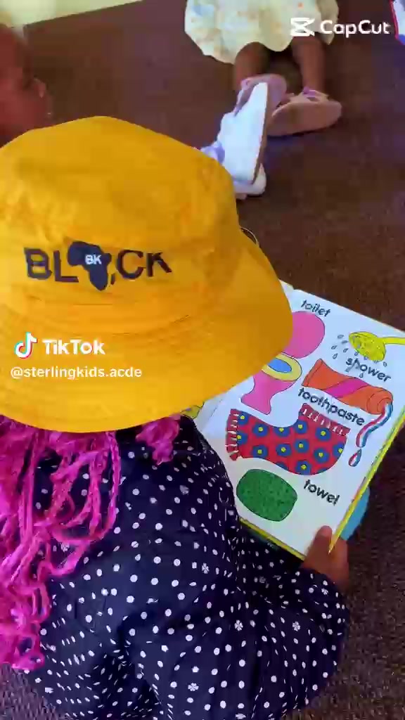 A little learner explores a colourful picture book in an academy video.